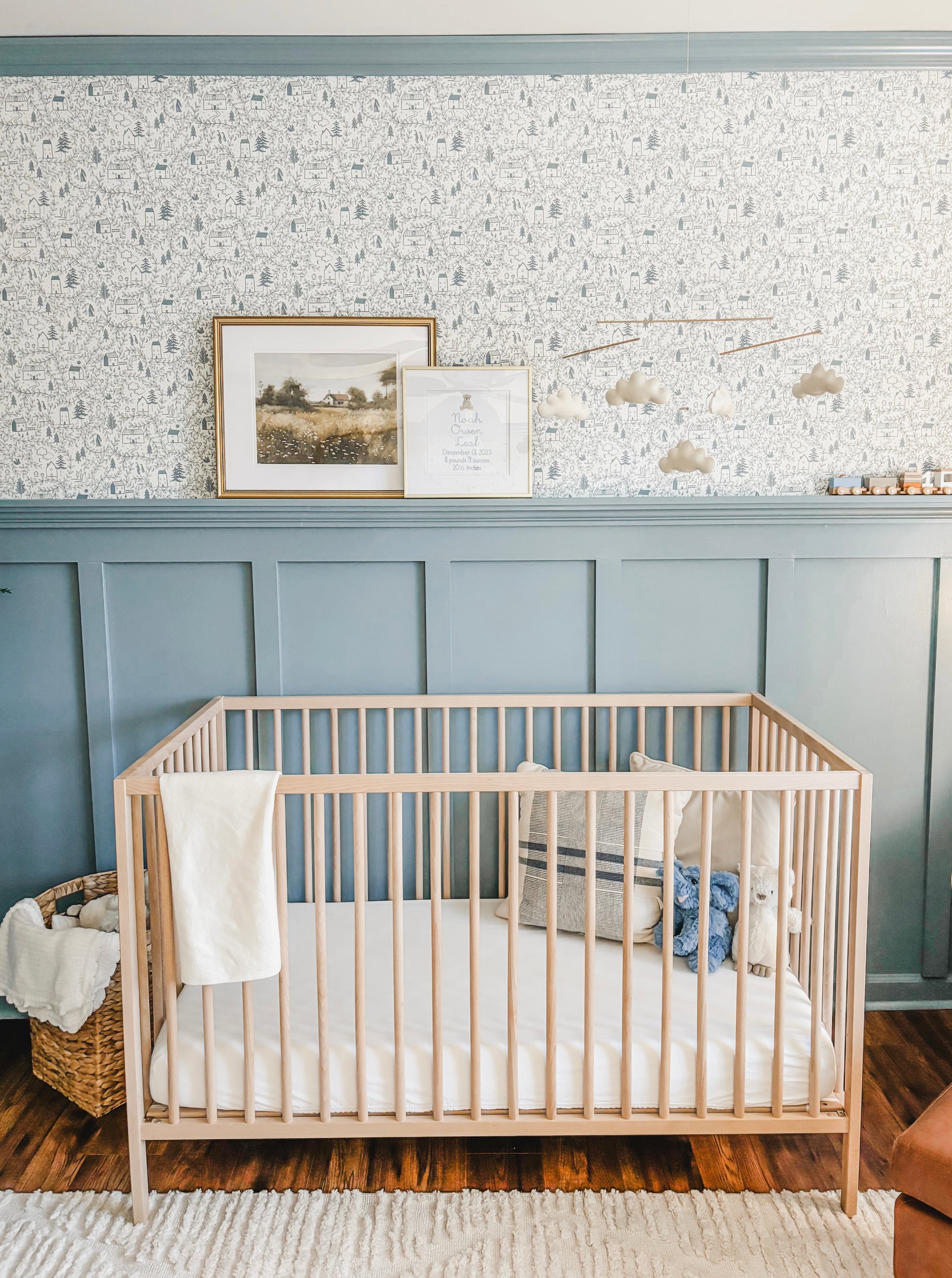 Baby boys nursery with blue wall panelling and Cottages in the Woods Wallpaper