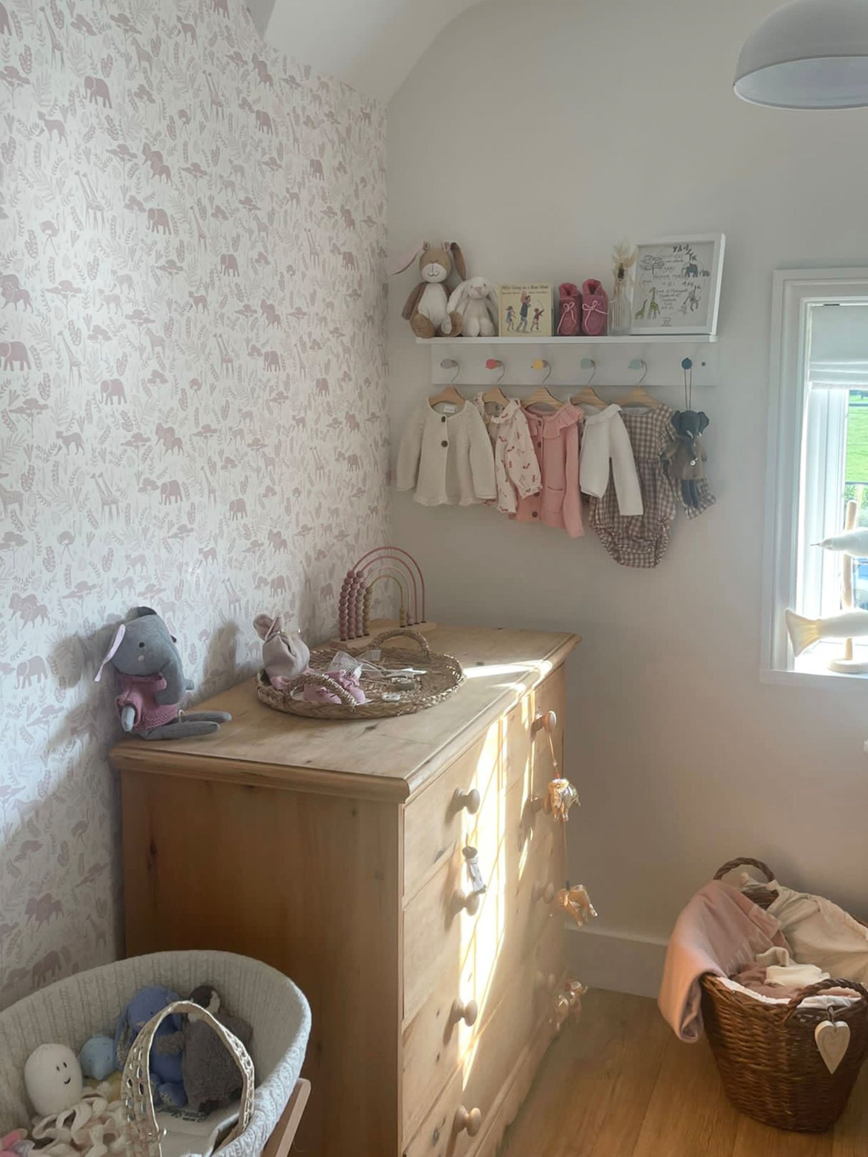 Ducks In A Row Wild Safari print wallpaper in Dusty Pink in Baby Girls nursery with chest of drawers and shelf